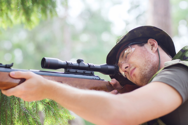 junger Soldat oder Jäger mit Gewehr im Wald Stockfoto 17559666