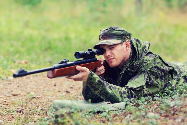 junger soldat oder jäger mit gewehr im wald Lizenzfreies Foto