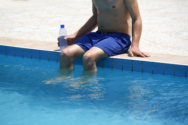 attraktive mann trinkt wasser im schwimmbad