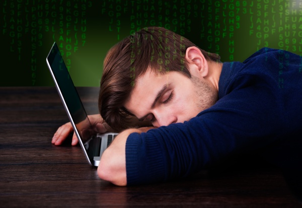 junger mann schlafend auf laptop
