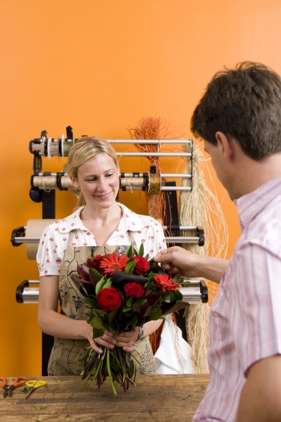 weibliche florist mit blumenstrauss fuer kunden