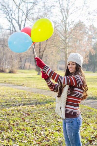 glueckliche junge frau mit bunten luftballons