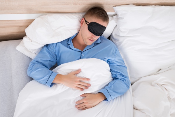 man schlafen auf bett tragen eyemask