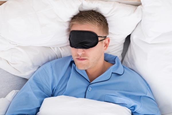 man schlafen auf bett tragen eyemask