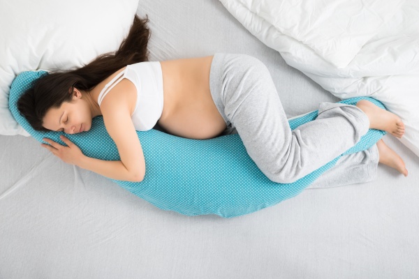 schwangere frau auf bett schlaeft