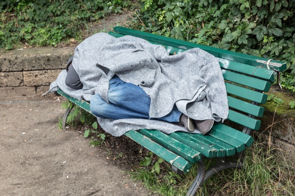 obdachloser mann schlaeft auf bank