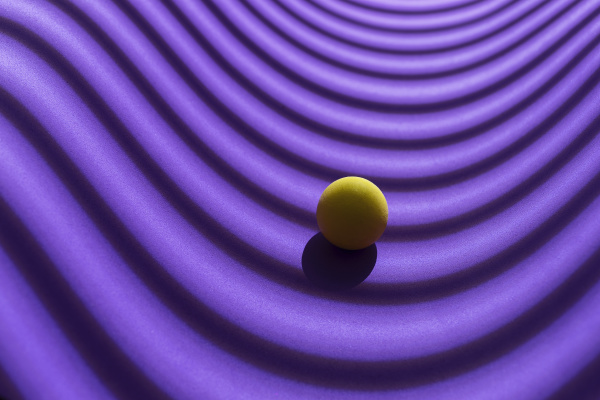 gelbe kugel ueber einem geometrischen violetten