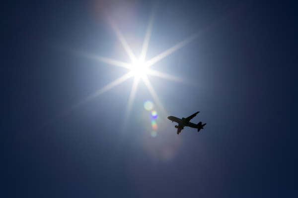 silhouette des flugzeugs vor einem sonnenstrahl