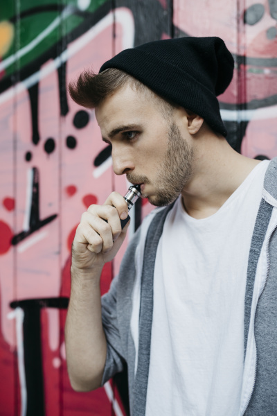 junger mann steht vor graffiti raucht