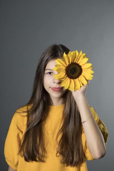 portraet eines laechelnden maedchens mit sonnenblume