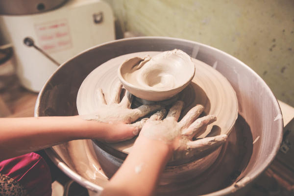 kinderhaende arbeiten mit ton auf keramikrad