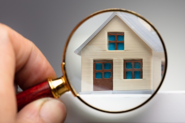 person looking house through magnifying glass