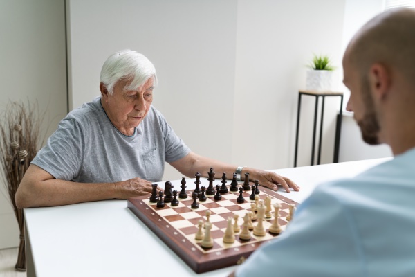 AEltere senior spielen schach mit betreuer