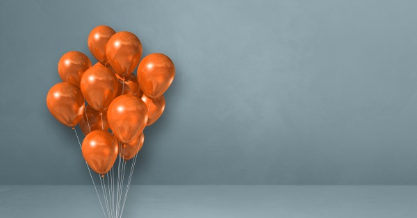 orangefarbene luftballons buendeln sich auf grauem