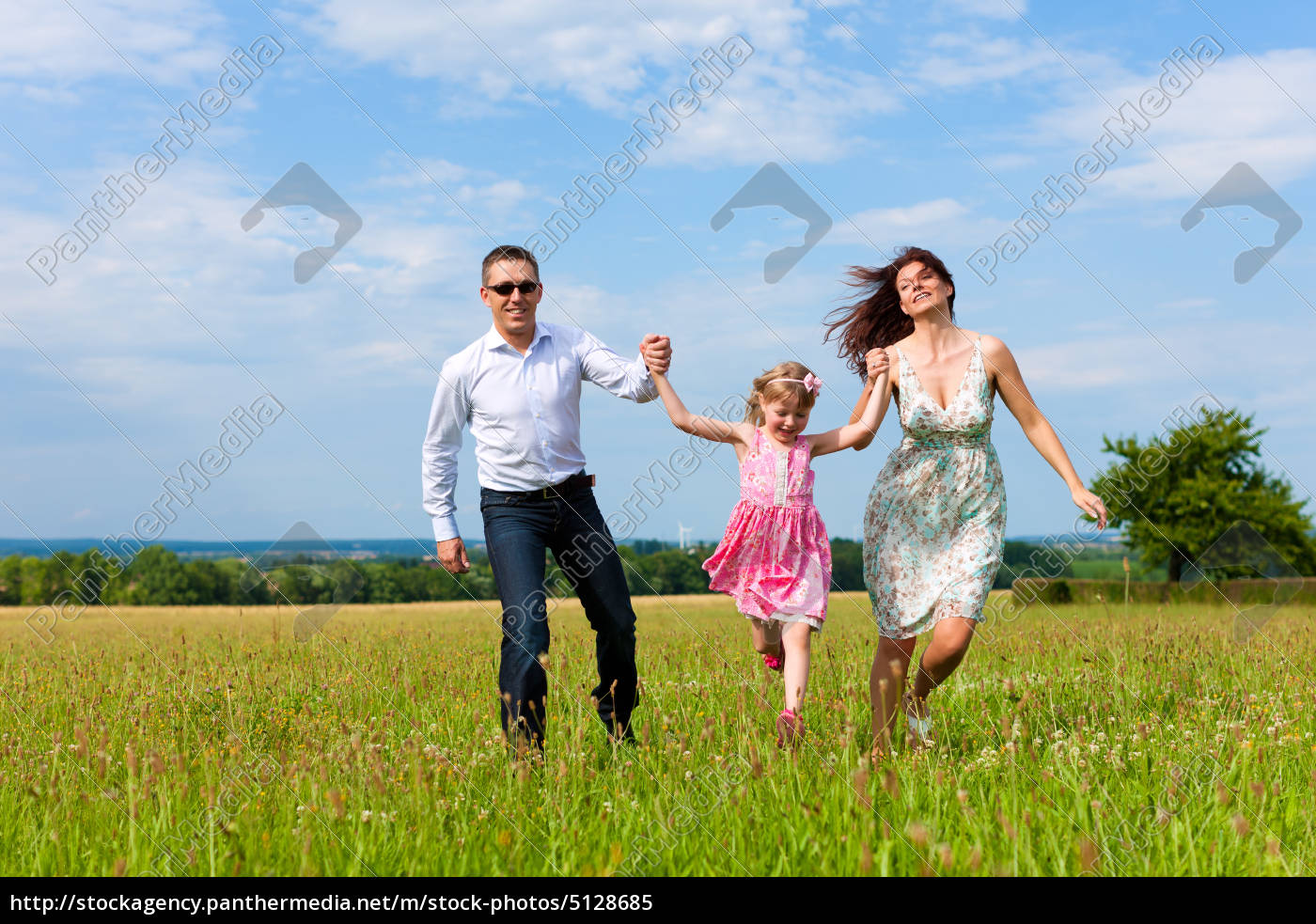 Glückliche Familie läuft auf einer Wiese im Sommer Lizenzfreies Bild