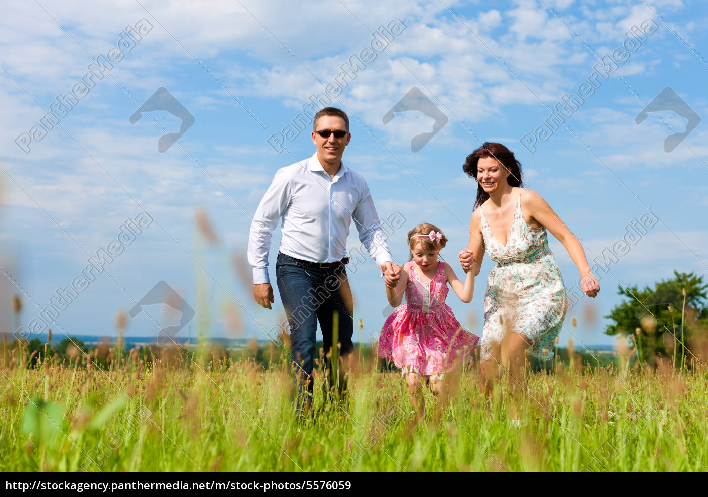 Glückliche Familie läuft auf einer Wiese im Sommer - Lizenzfreies Bild