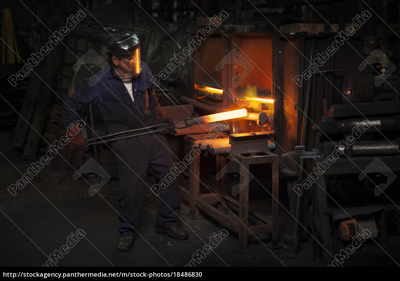 Forge worker pre heating steel billet for forging in - Stock Photo